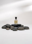 Small bottle with a label on a stack of stones against a white background