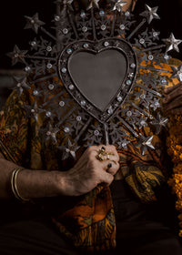 Hand holding a decorative mirror with star and heart design against a dark background